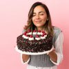 Young woman holding birthday cake over isolated pink background
